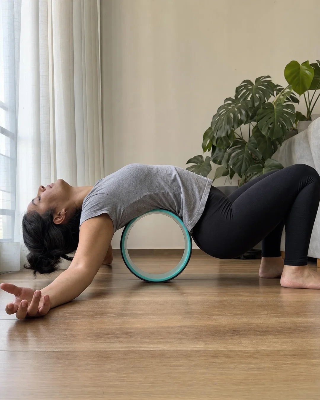 Mujer arqueada sobre la rueda, con la rueda entre los omóplatos y los brazos abiertos